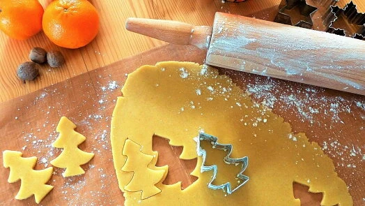Žluté těsto na sušenky tvarované válečkem a formičkami do stromků.