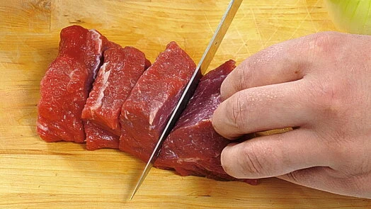 Rozkrojování surového masa na plátky pro guláš.