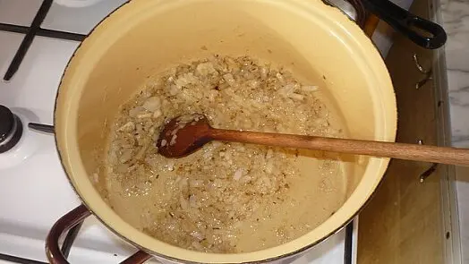 Cibule s kořením se smaží v hrnci na guláš.