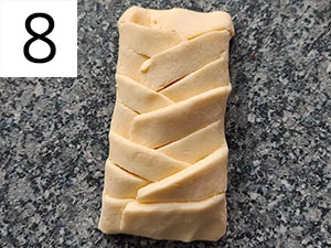 Krok v příprave: plněný těsto se plete do braided tvaru.
