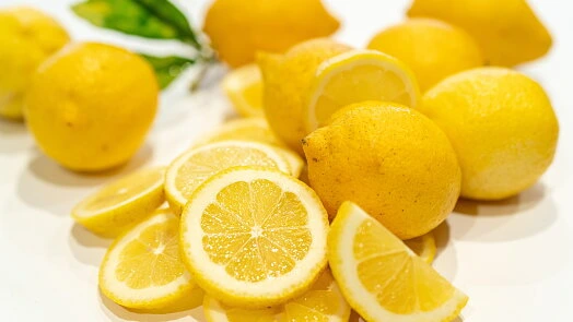 Žluté citrony, celé i nakrájené na kolečka.