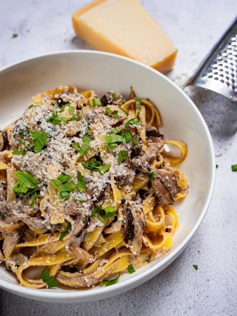 Mísa těstovin s houbovou smetanovou omáčkou posypaná parmezánem.