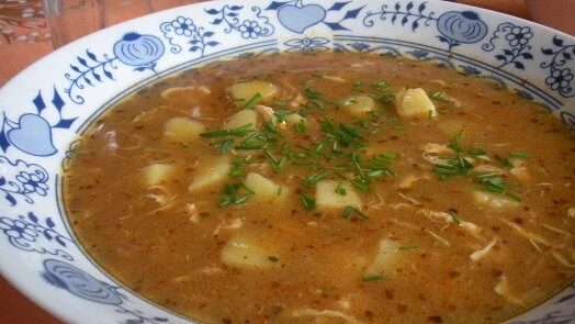 Hot kmínová polévka s bramborami v zdobené misce.