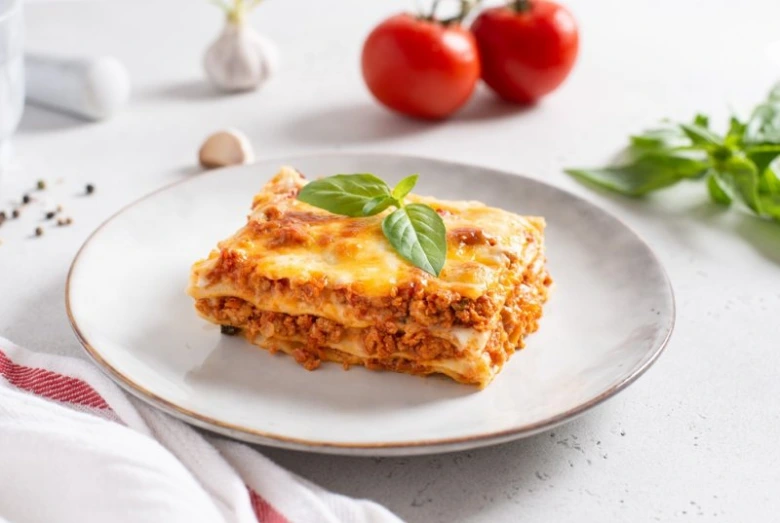 Kousek pečené lasagne s bazalkou na talíři