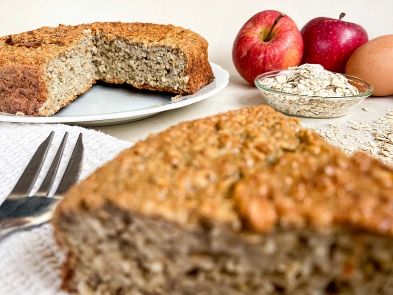 Kousek jablkového koláče z ovesných vloček s surovými ingrediencemi.