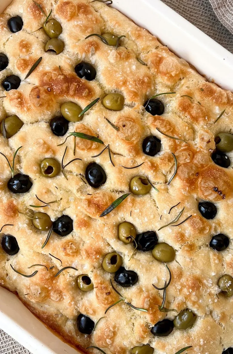 Focaccia s olivami a rozmarýnem po upečení v bílé formě.