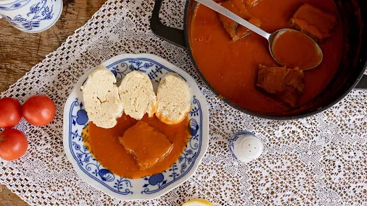 Hot rajska omacka s chlebem v misce na ubrusu.