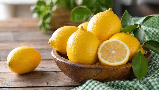 Čerstvé citrony v dřevěné mísce s listem.