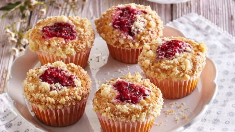 Zlatohnědé malinové muffiny s křupavým vrstvením na talíři.