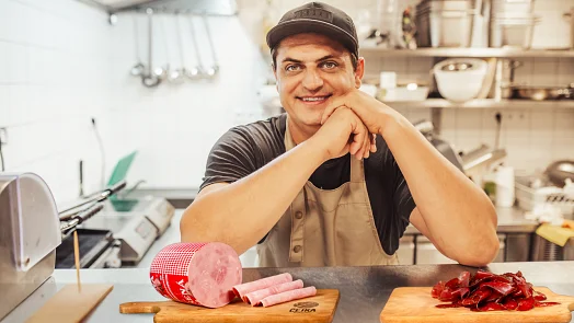 Šéfkuchař s nakládaným masem na kuchyňském pultu.