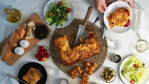 Svěží pečená lasagne podávána s chlebem a salát.