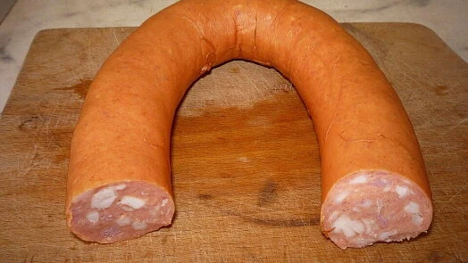 Surová saláma na dřevěném prknu pro pomazánku.