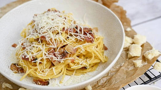 Připravená spagetti karbonará s šunkou a syrem v misce.