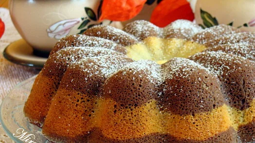 Jogurtová bábovka s vrstvami posypaná moučkovým cukrem.